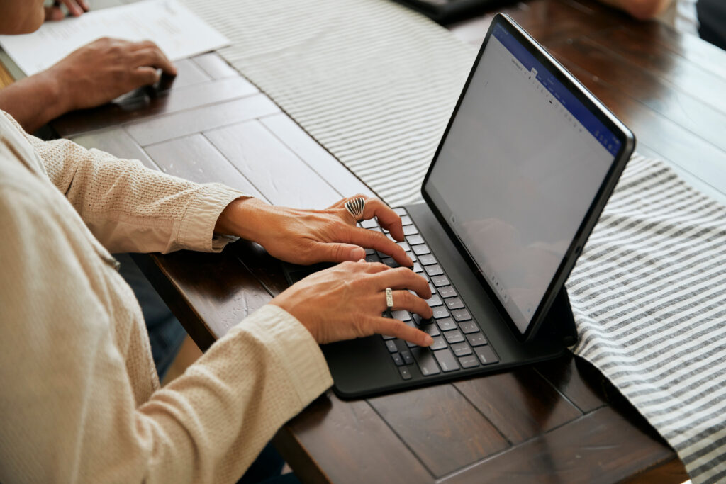 Board member using a laptop and smartphone at a desk