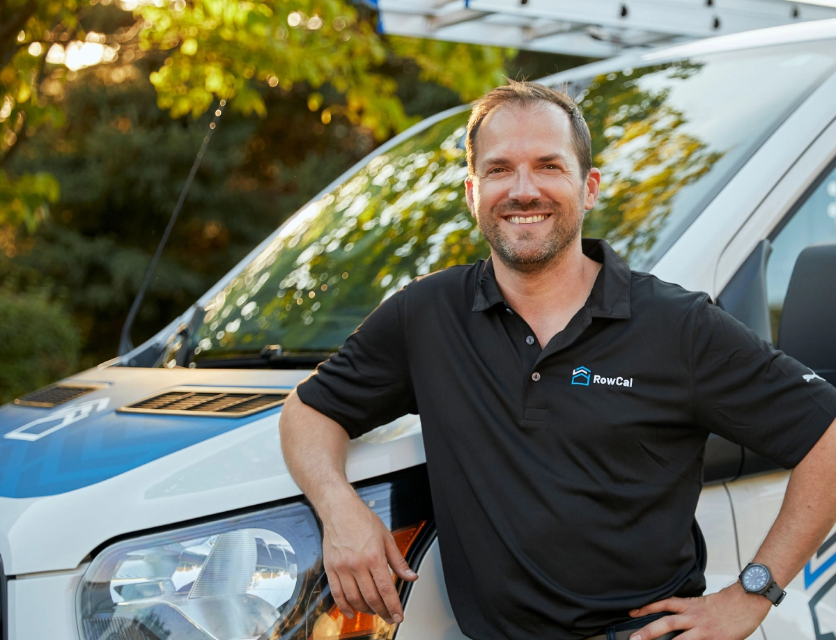 RowCal team member by a branded van in a residential community, ready to assist.